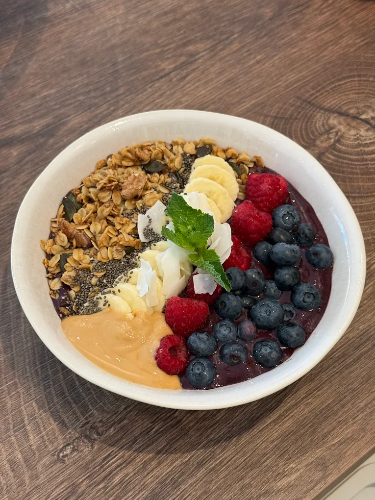 Acai Bowl mit Granola, Banane, Kokoschips, Beeren und Erdnussmus